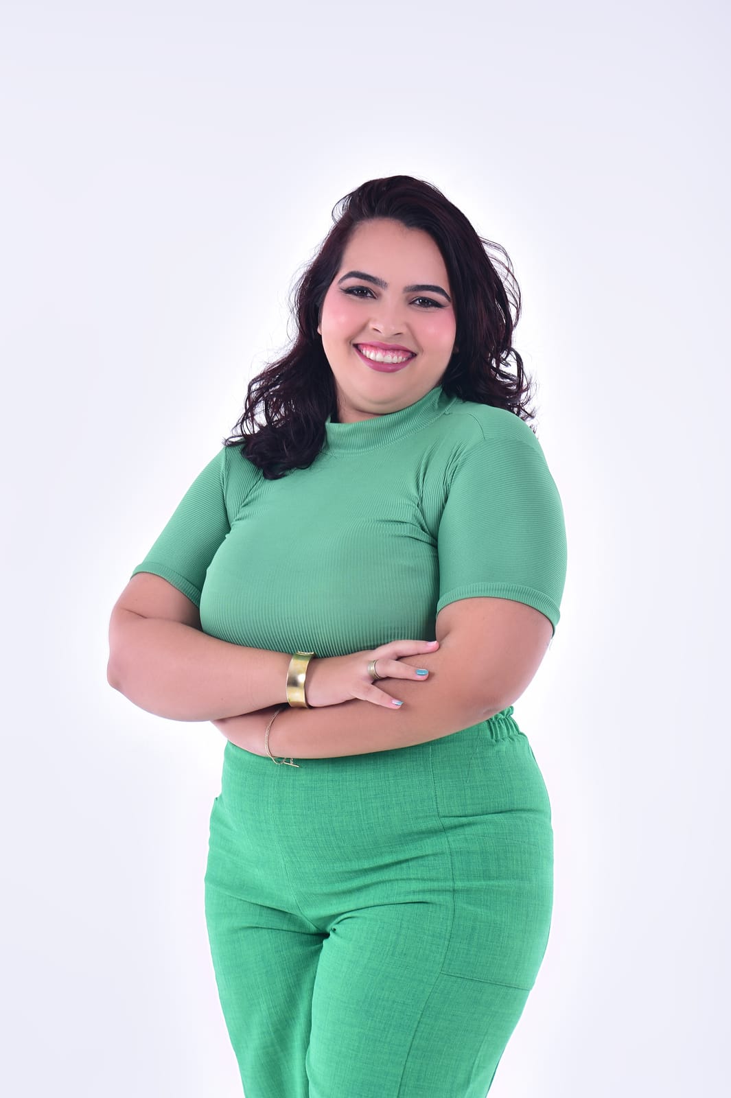 Victoria Elizabeth Brasilino, psicóloga clínica, sorrindo de braços cruzados, com blusa e calça verdes